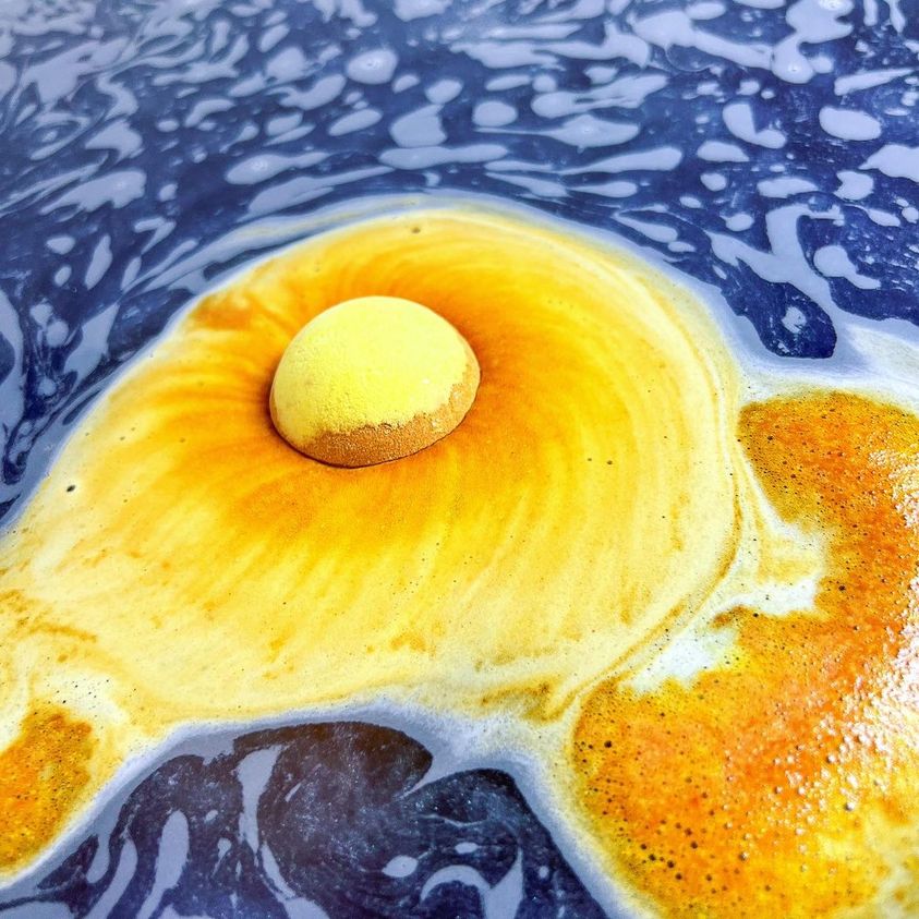 Saturn-inspired bath bomb fizzing in water with swirling cosmic colours